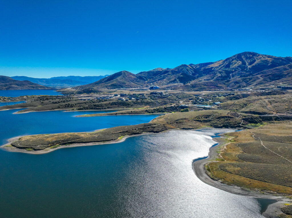 A serene view of Jordanelle Reservoir, featuring paddle boarding, kayaking, and fishing, with stunning lake views and nearby trails.